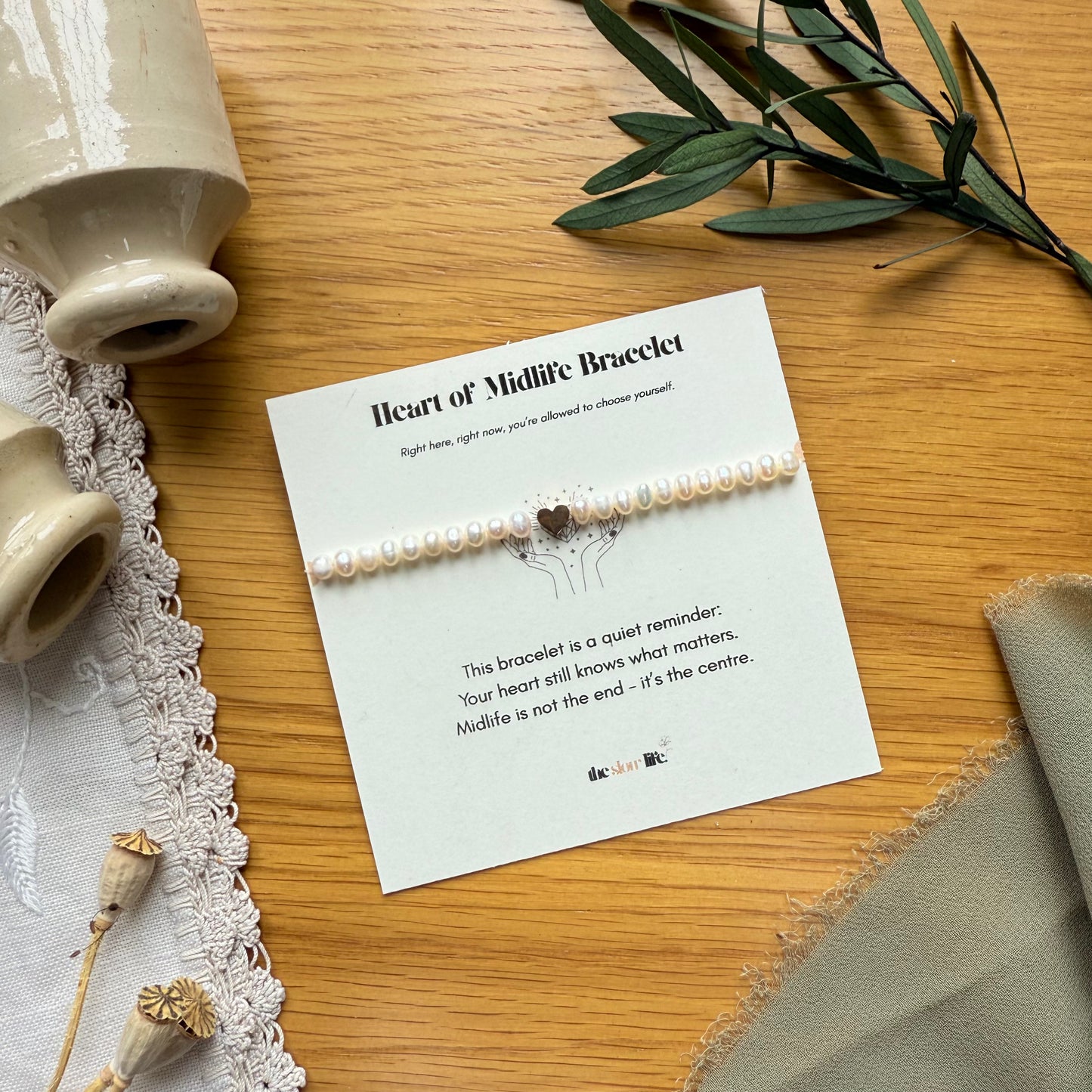 Pearl bracelet on a card with decorative elements on a wooden surface