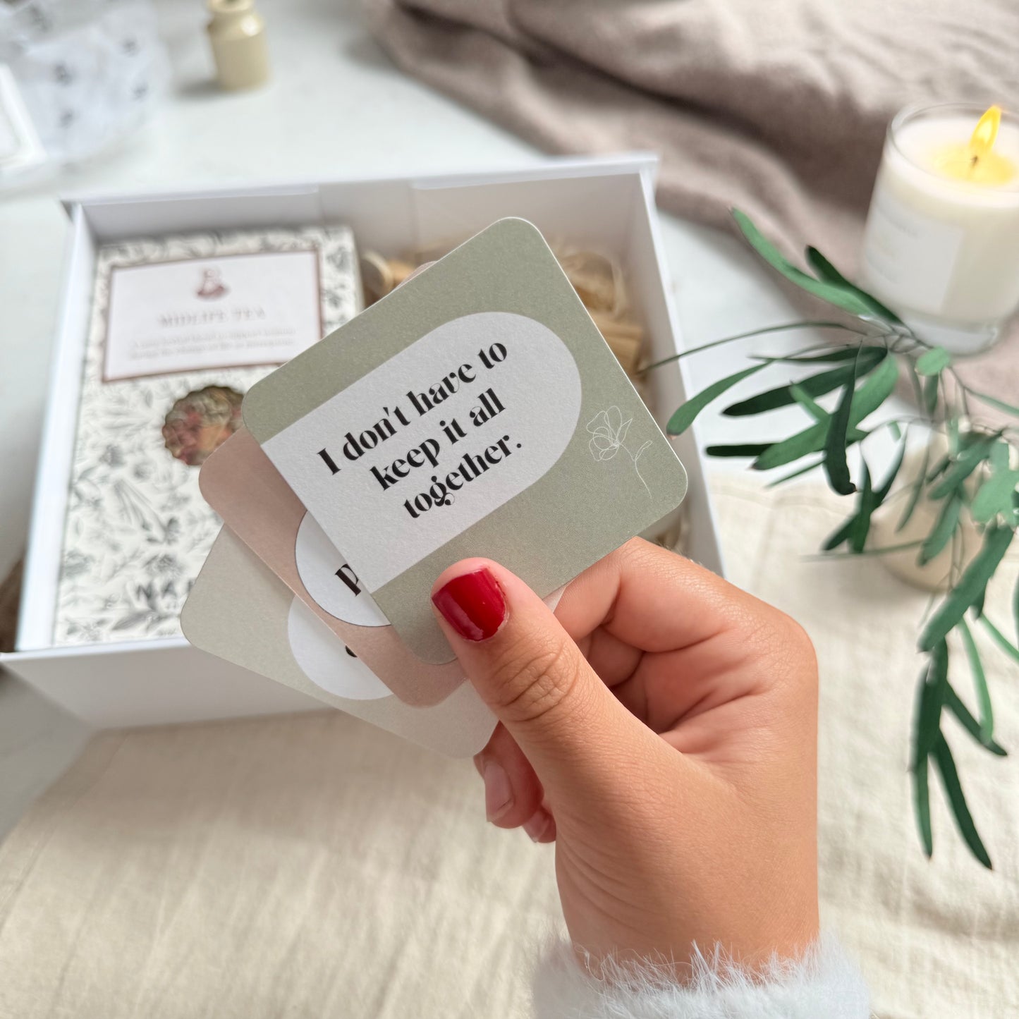 Hand holding a card with text 'I don't have to keep it all together' in a cozy indoor setting.