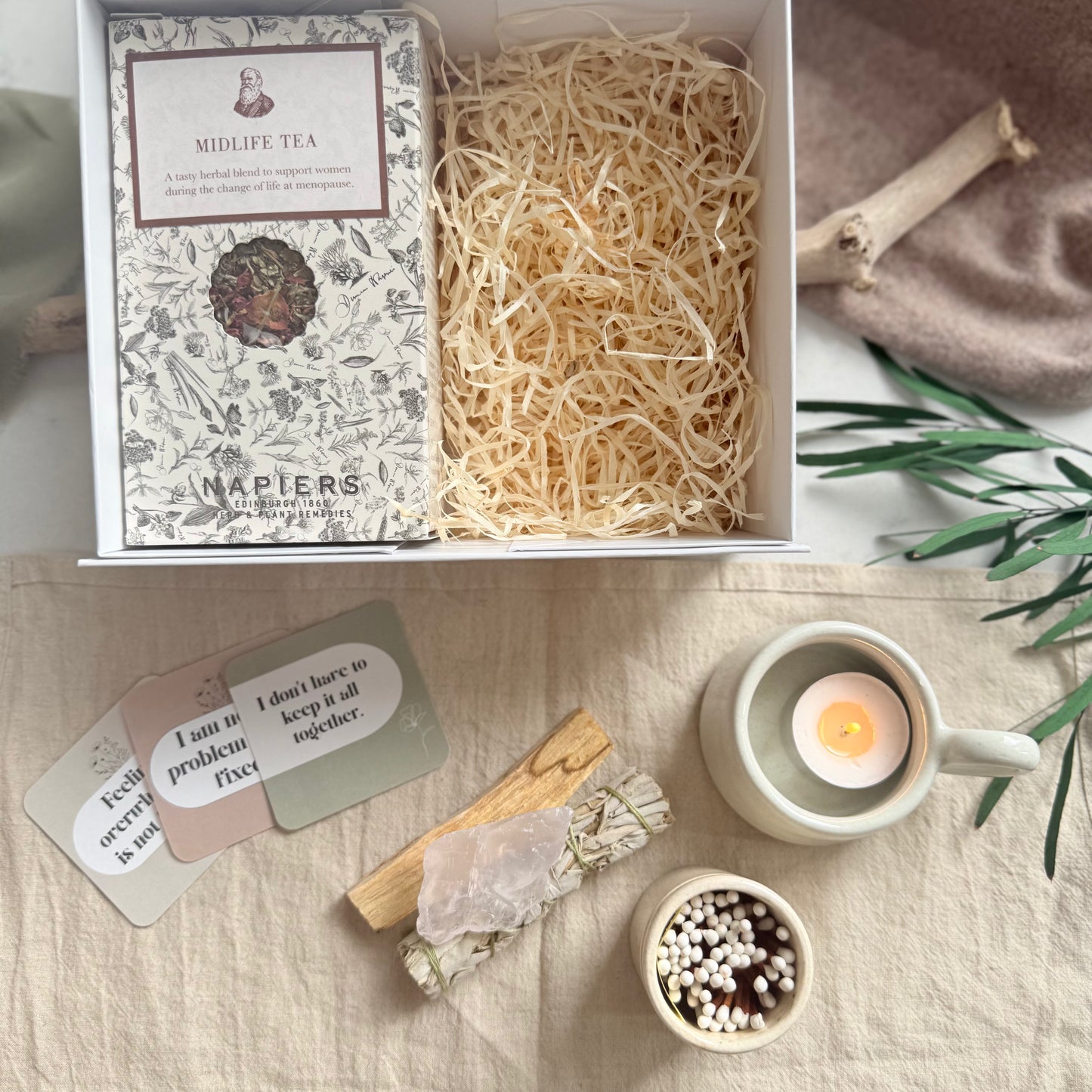 Tea packaging with cards and a candle on a textured surface