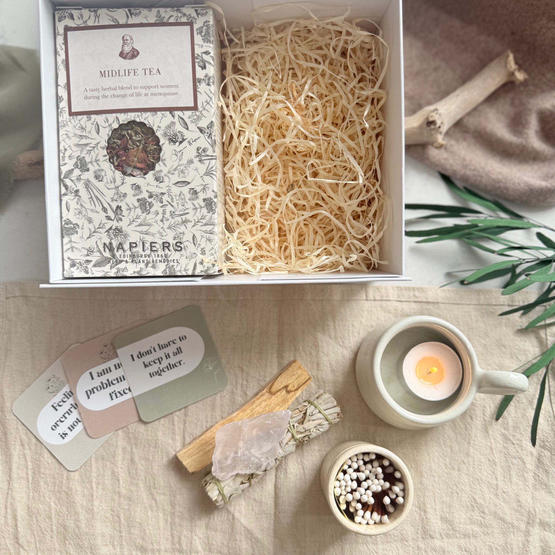 Tea packaging with cards and a candle on a textured surface