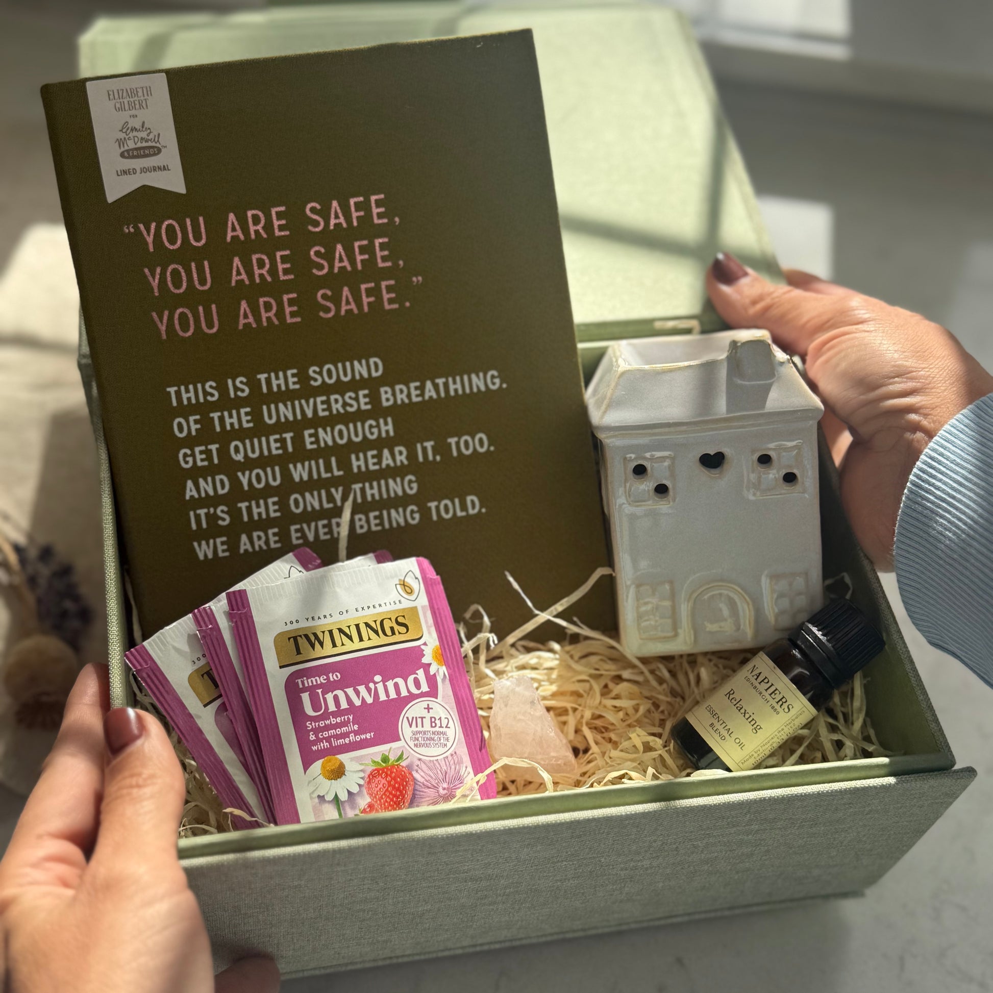 Gift box with tea packets, a small lamp, and a card inside.