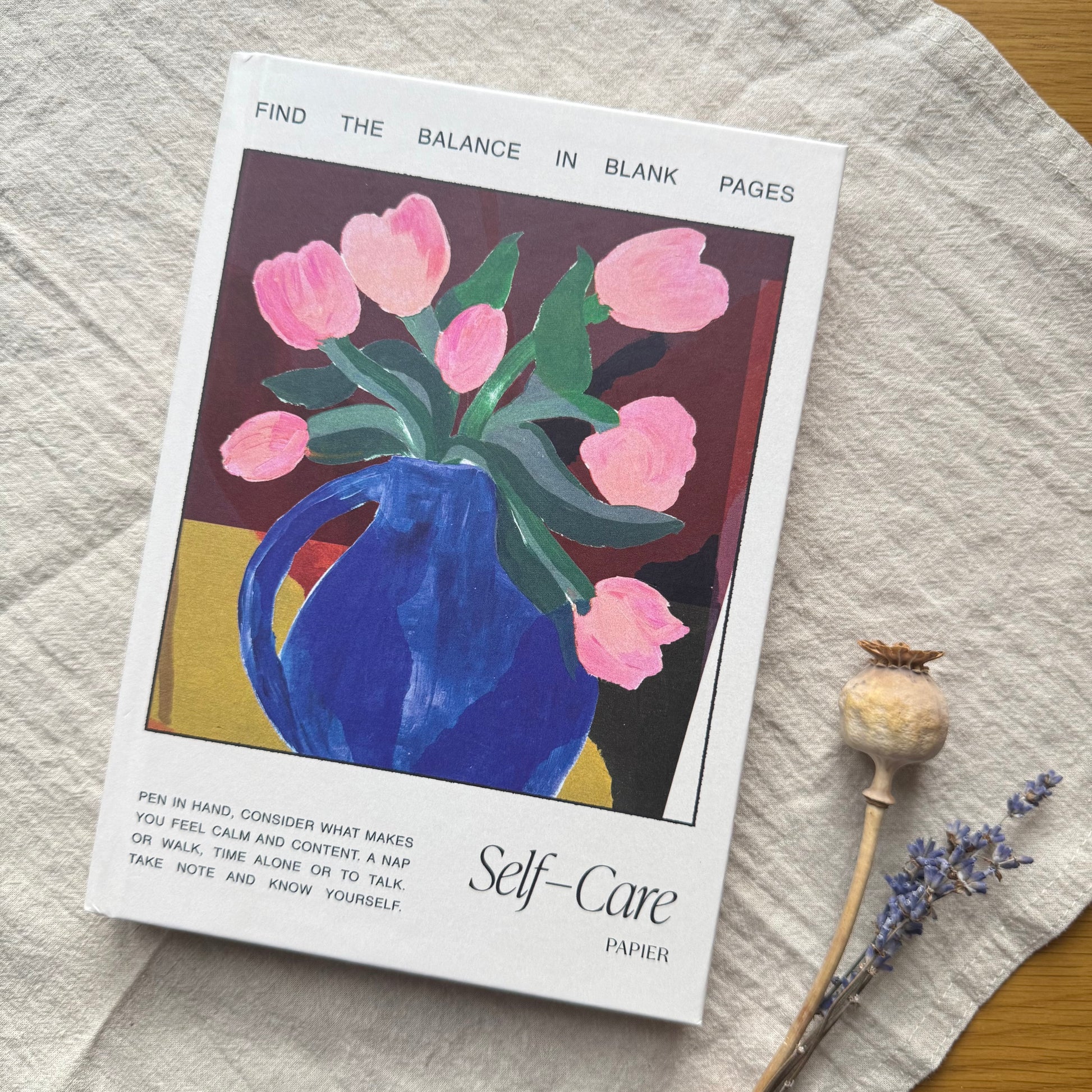 Booklet titled 'Self-Care' with a blue vase and pink tulips on a textured surface.