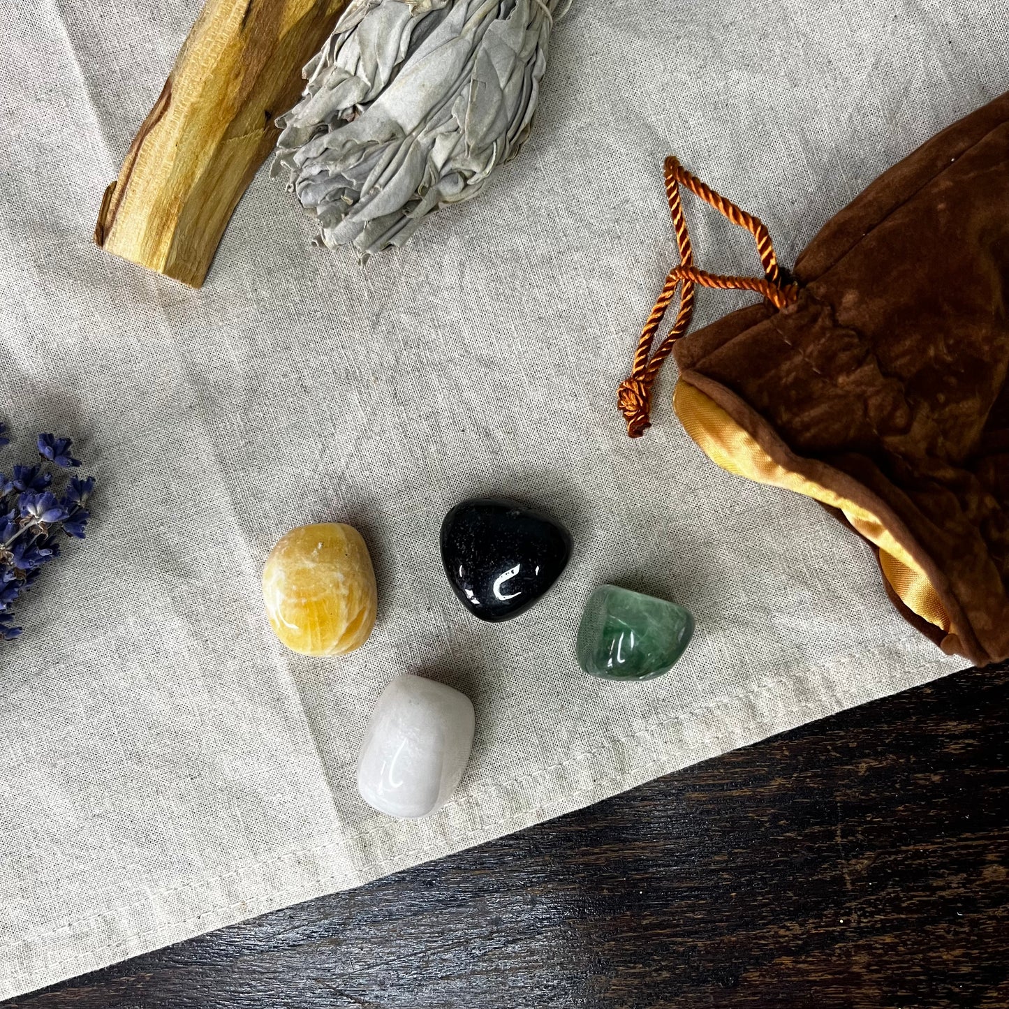Mindfulness Crystal Set featuring Orange Calcite, Green Fluorite, White Onyx, and Black Agate, beautifully arranged on a wooden surface with a brown velvet bag.