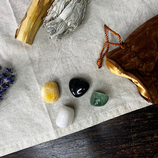 Mindfulness Crystal Set featuring Orange Calcite, Green Fluorite, White Onyx, and Black Agate, beautifully arranged on a wooden surface with a brown velvet bag.