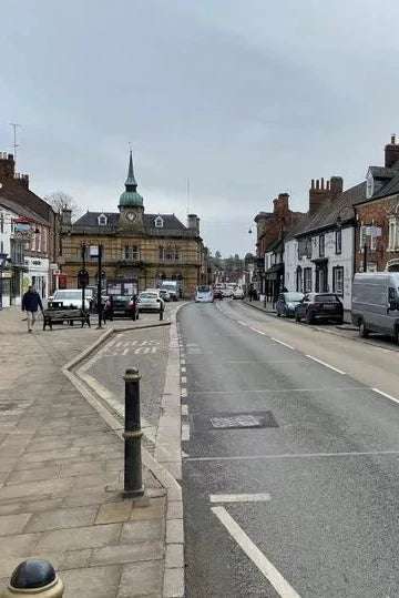 Town street with shops and cars on a cloudy day